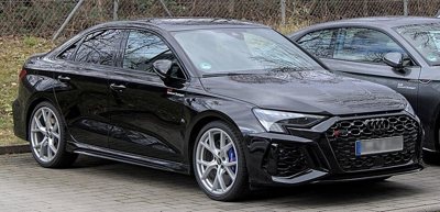 Black Audi RS3 sedan parked on a paved area with visible front and side profile showing sleek design and alloy wheels