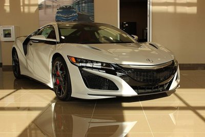 white Acura sports car displayed indoors with sleek design and red brake calipers on black wheels