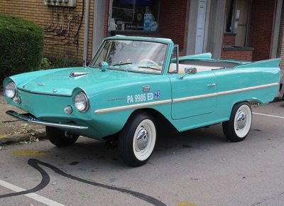 aqua blue vintage Amphicar convertible with whitewall tires parked on the street in front of a brick building