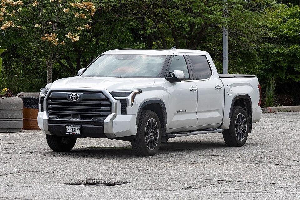 white Toyota Tundra pickup truck parked on a paved surface with trees in the background