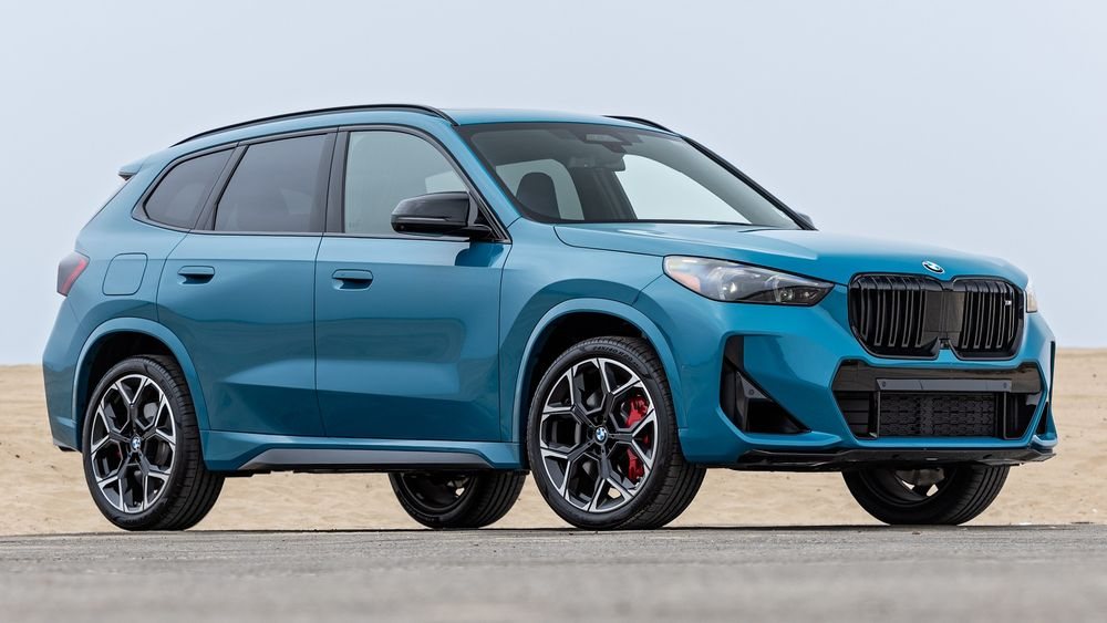 blue BMW compact SUV parked on a road with sandy background showing front and side view