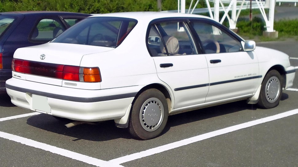 White sedan rear and side view with hubcaps and four doors