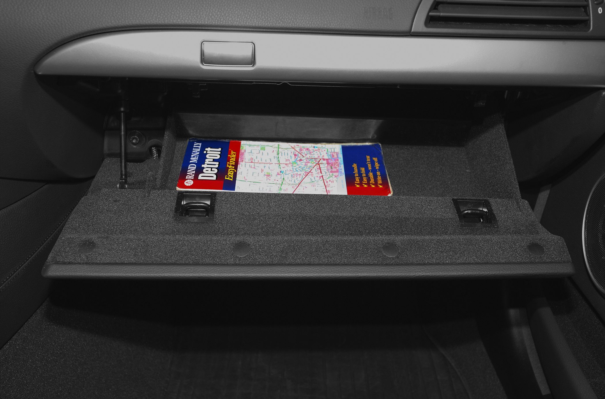 Open glove compartment with a map inside and dashboard trim detail