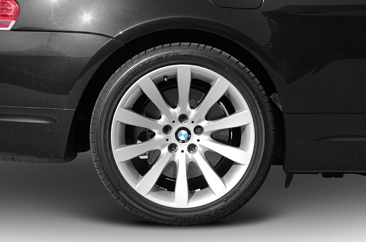 Silver 10-spoke alloy rim with Bridgestone tire on a black vehicle.