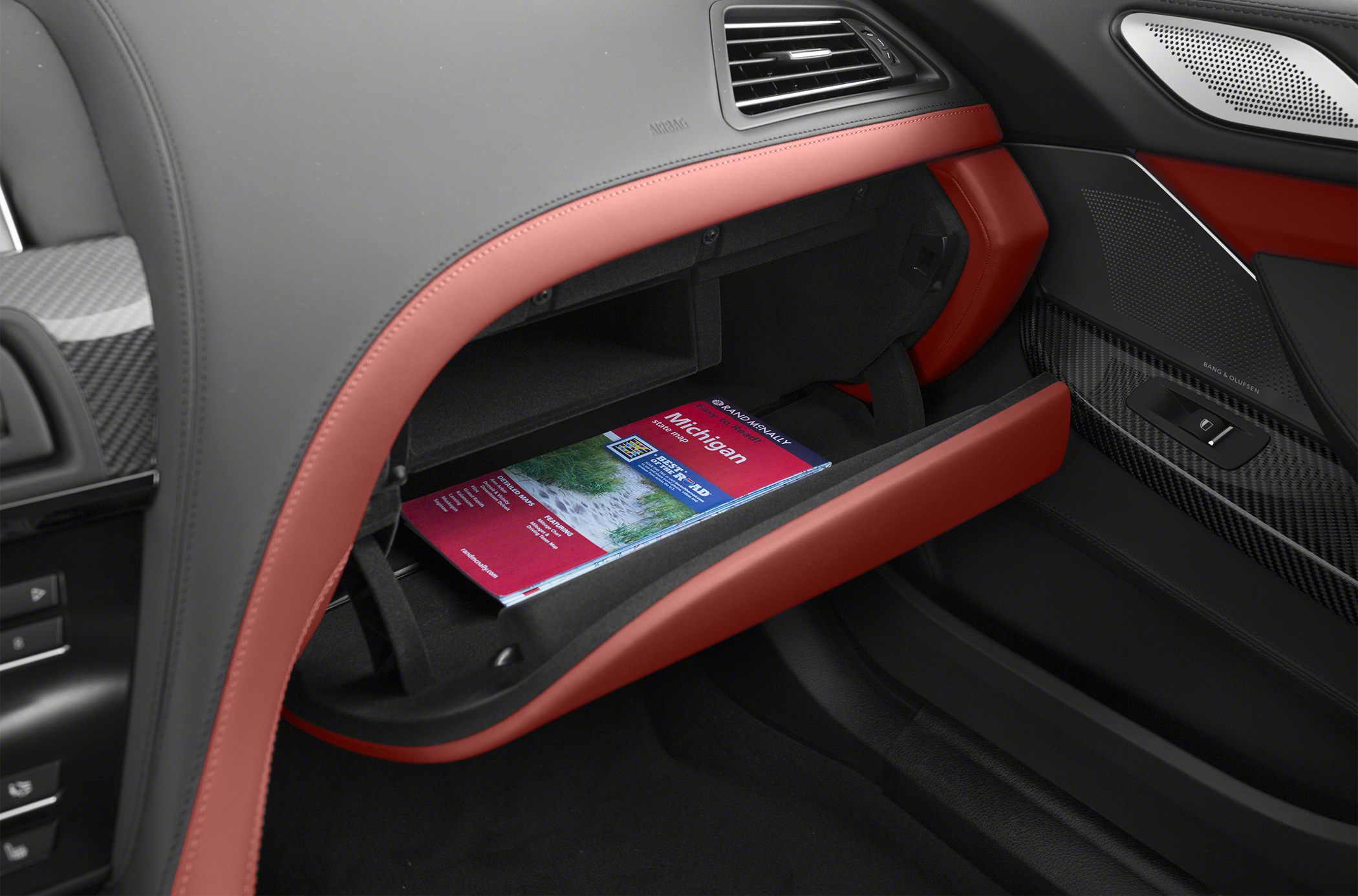 Open glovebox with red leather trim and carbon fiber door panel
