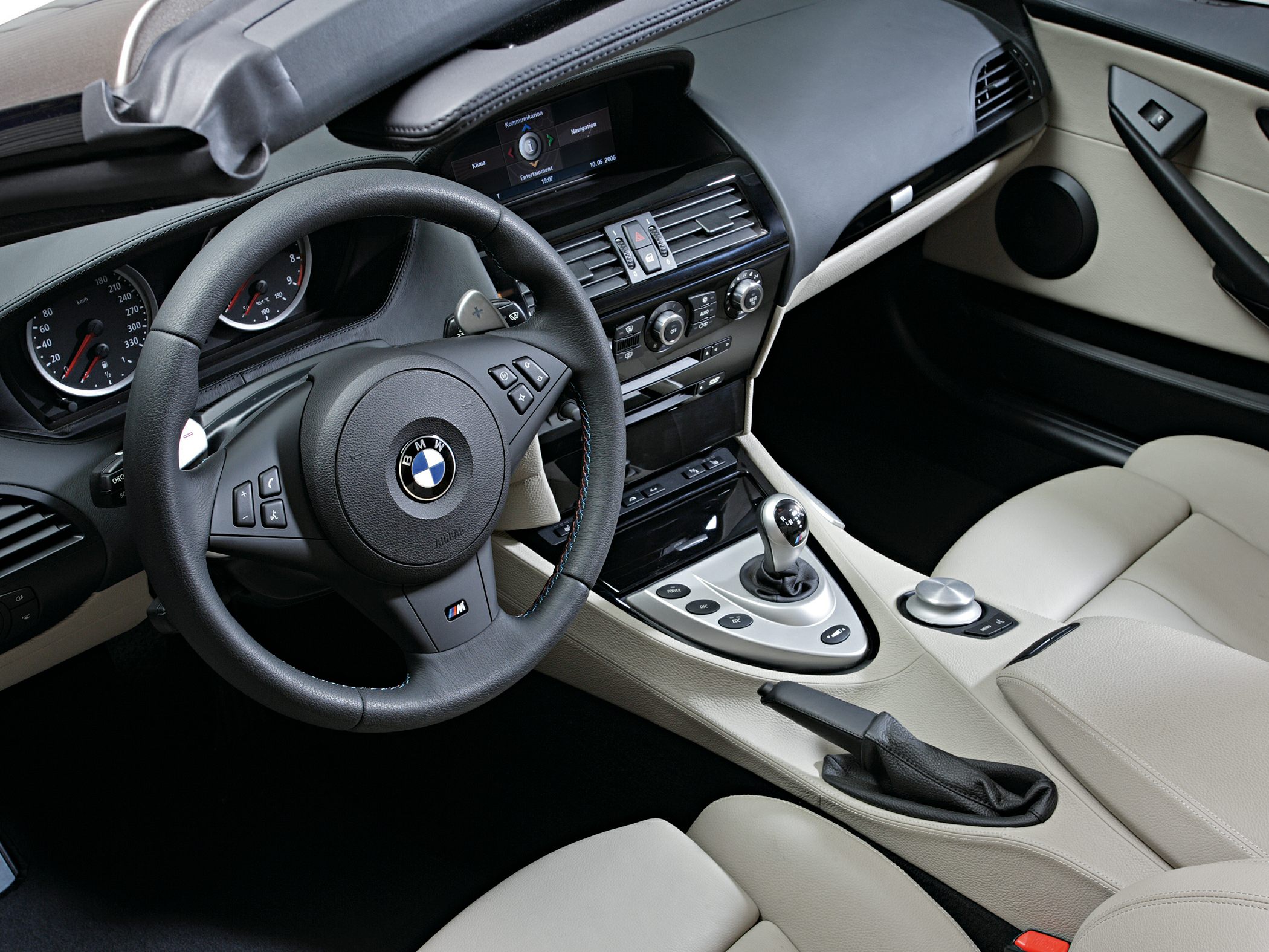 Steering wheel, dashboard, beige leather seats, and center console controls.