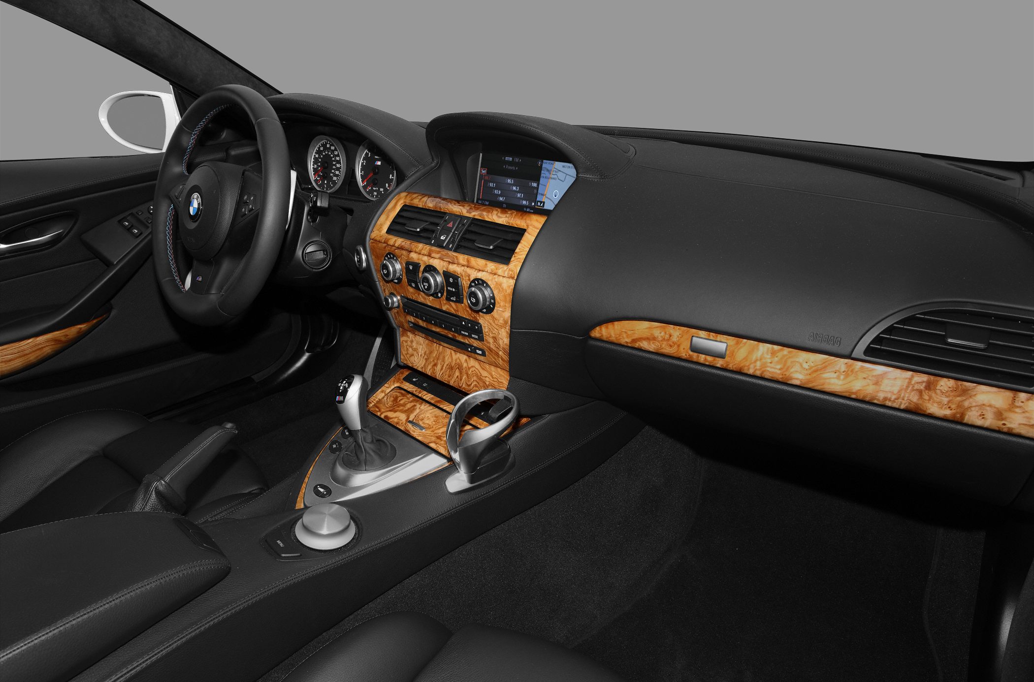 Wooden trimmed dashboard and center console with infotainment screen and black leather interior