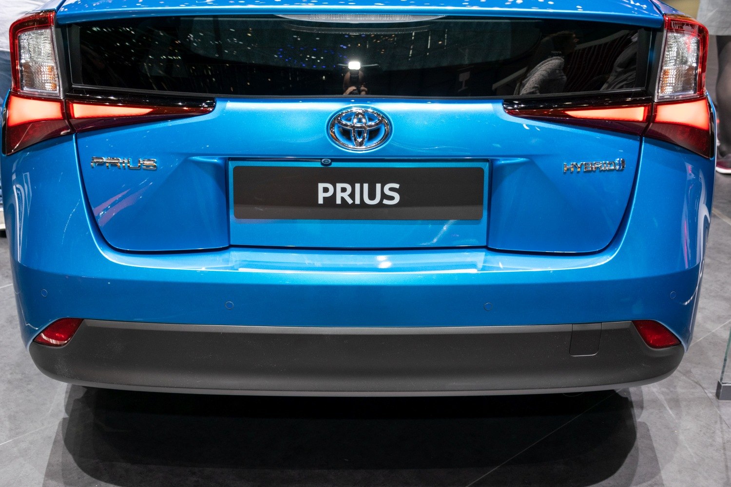 Rear view with taillights and hybrid badge of a blue hybrid vehicle