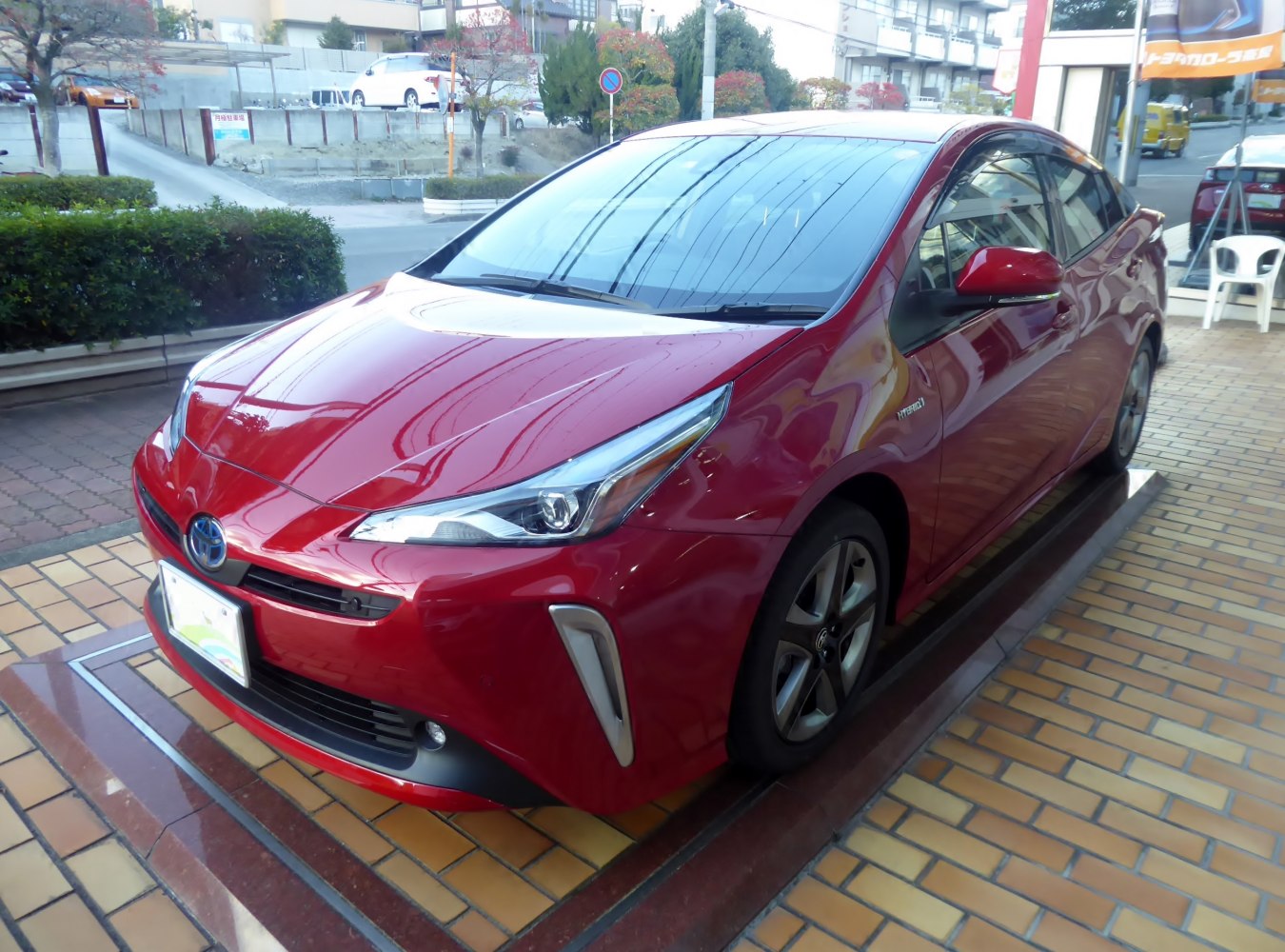 Red hybrid hatchback with sleek headlights and aerodynamic front.