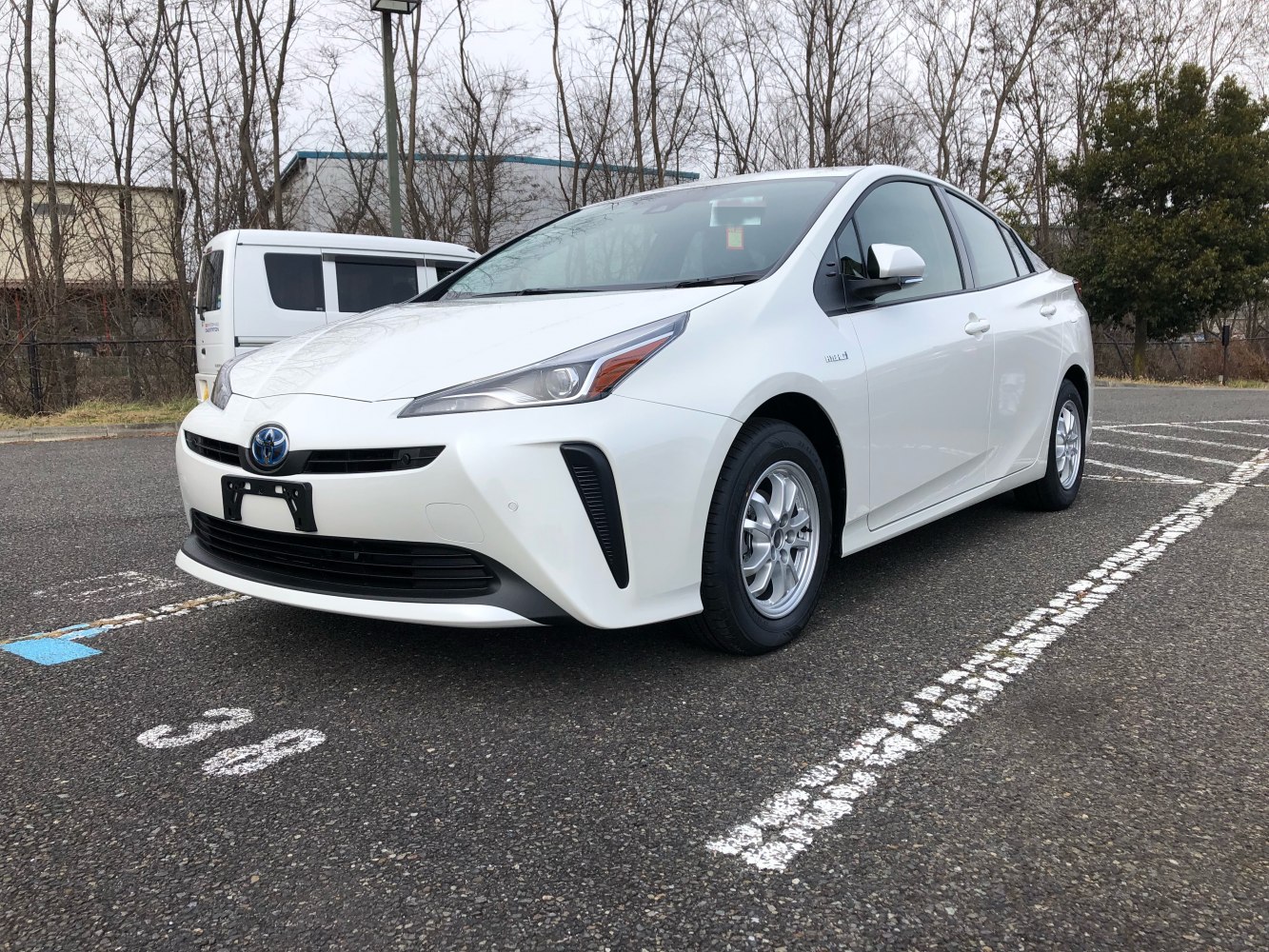 White hybrid sedan front-side view with sleek headlights and alloy wheels