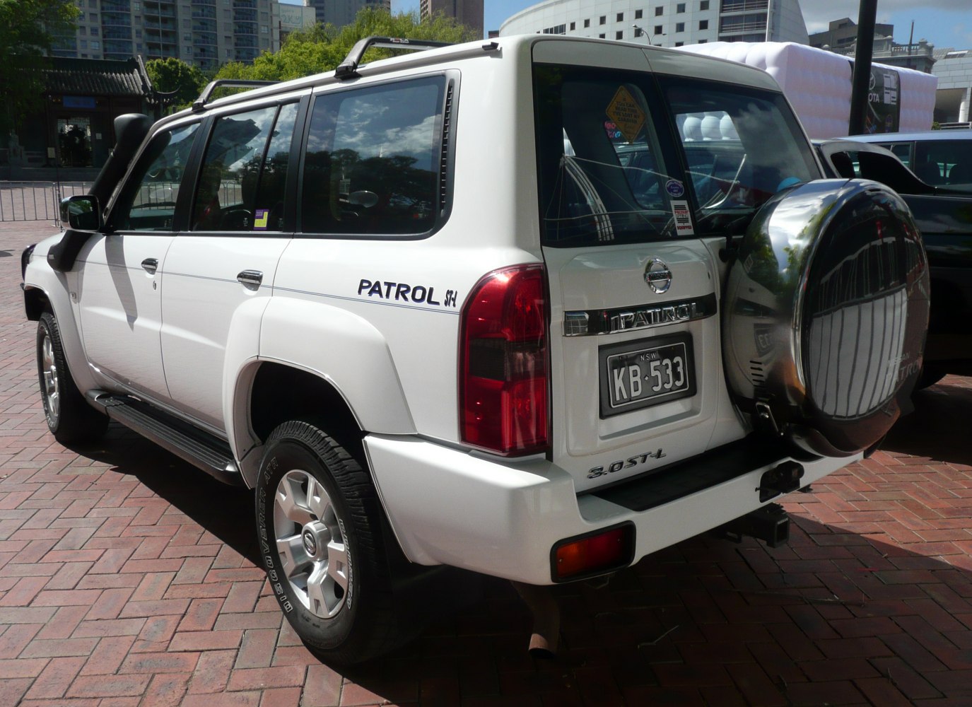 Rear and side view of white 5-door SUV with spare tire and roof rack