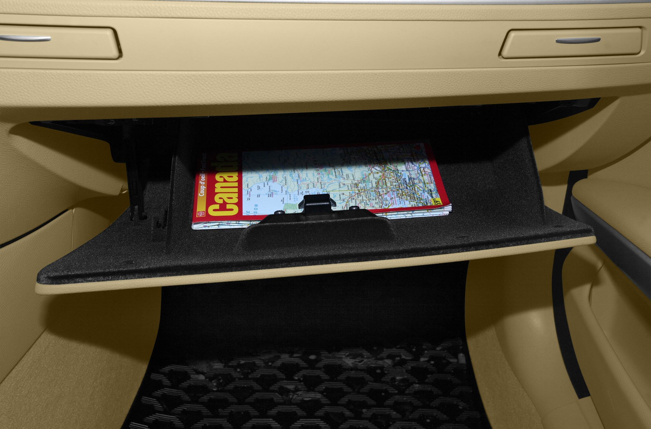 Open glove compartment with map inside in beige car interior