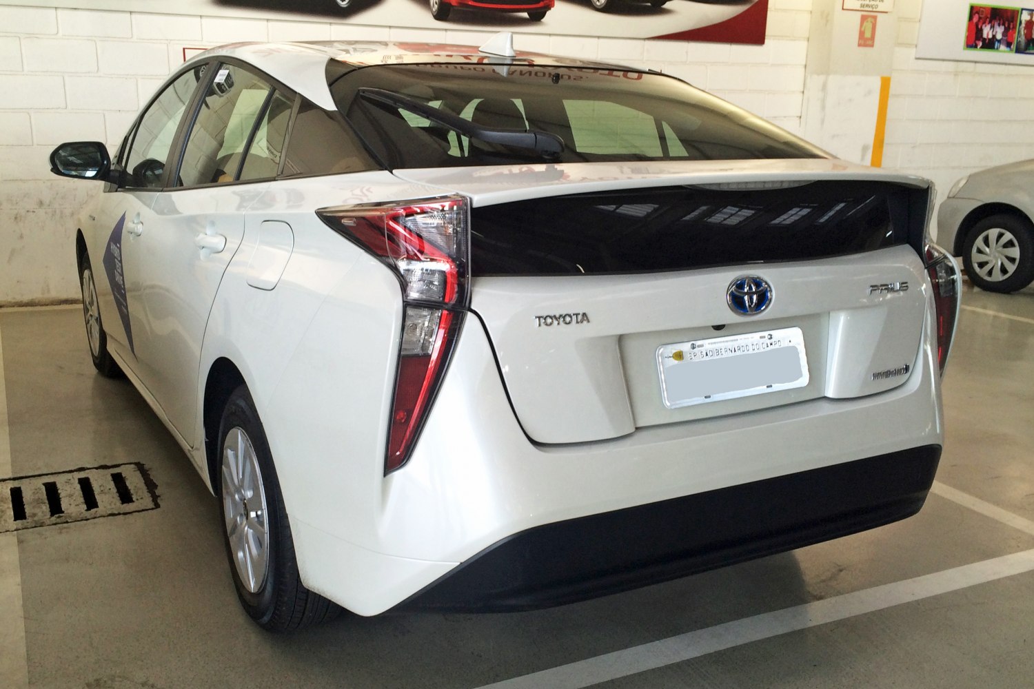 White hybrid vehicle rear with vertical multi-segmented tail lights and large black rear hatch window.