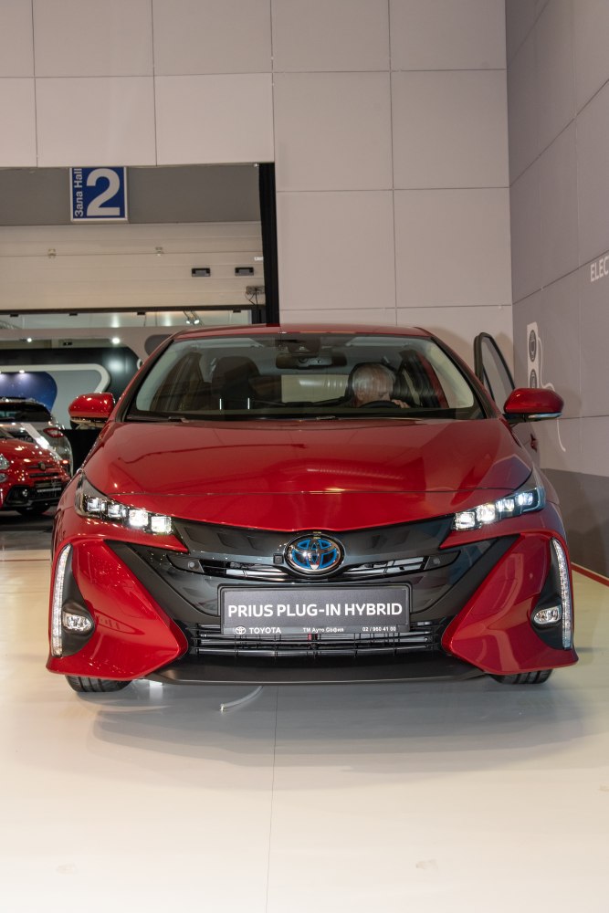 Front view of a red plug-in hybrid with sleek headlights and aerodynamic styling.