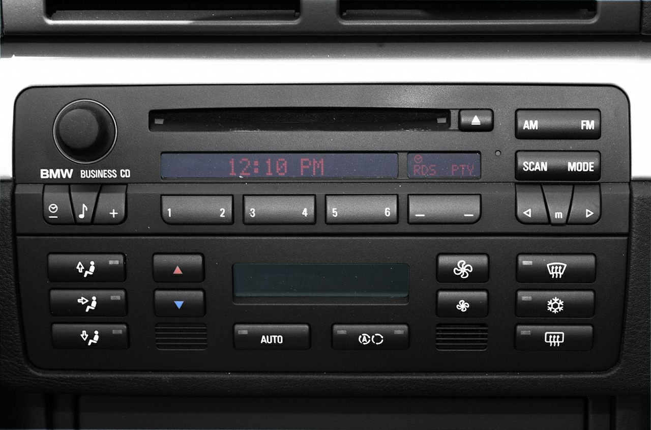 Close-up of car stereo and climate control panel with buttons and digital display.