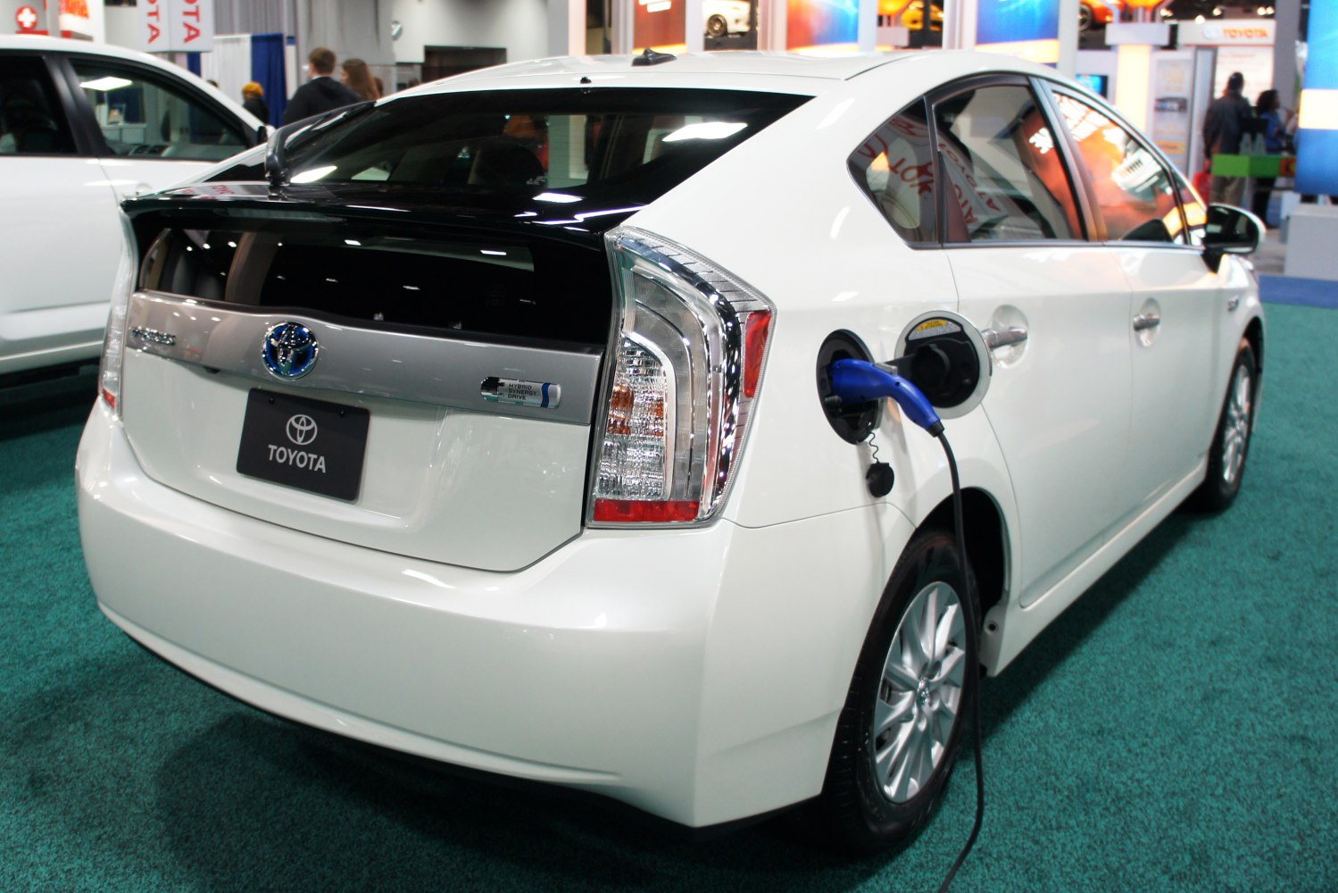 Rear view of hybrid hatchback with electric charging port and cable.