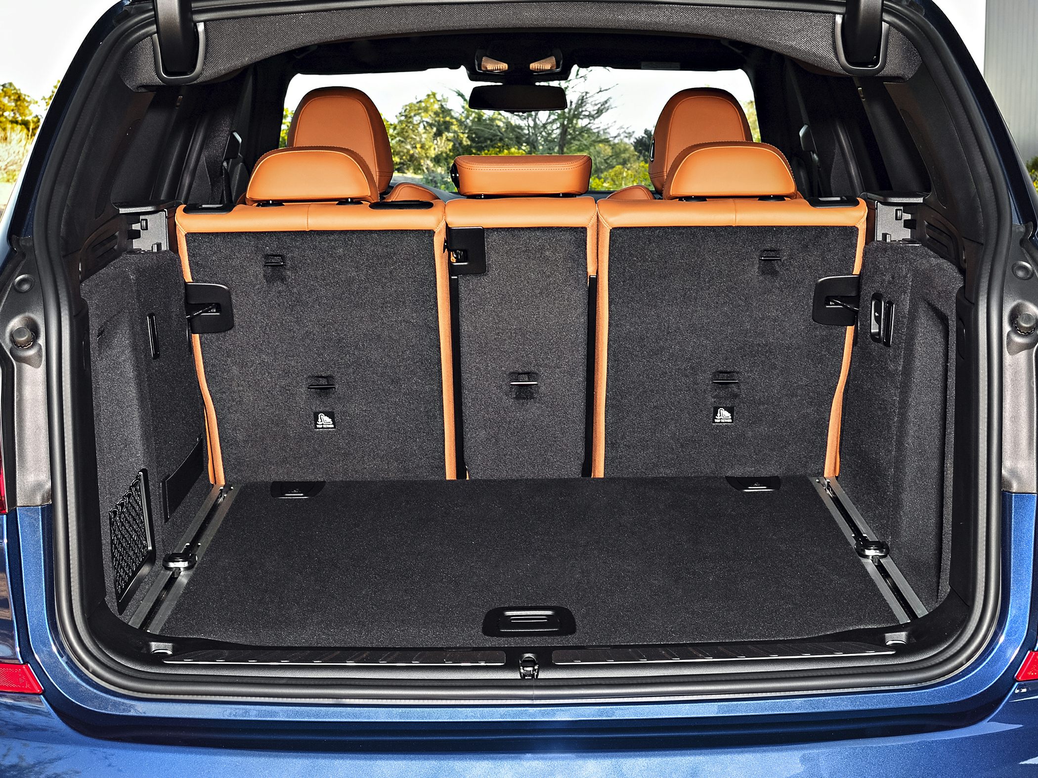 Rear cargo area with folded rear seatbacks and tan headrests, spacious interior storage