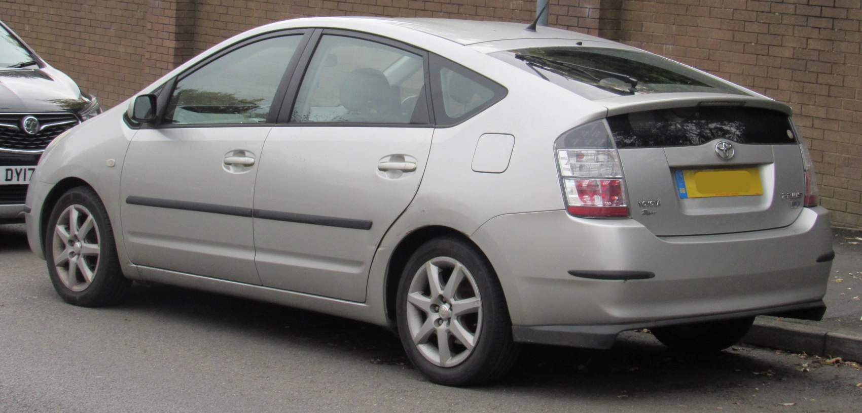 Silver hybrid hatchback rear side view with distinct taillights and rear window spoiler