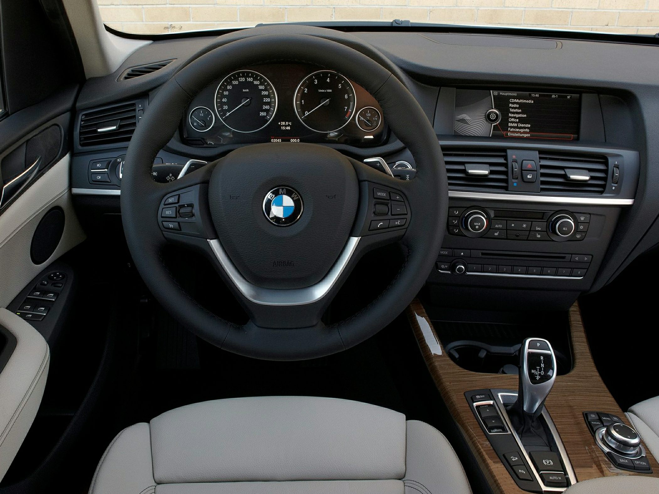 BMW interior with steering wheel, dashboard, and wood-trimmed center console.