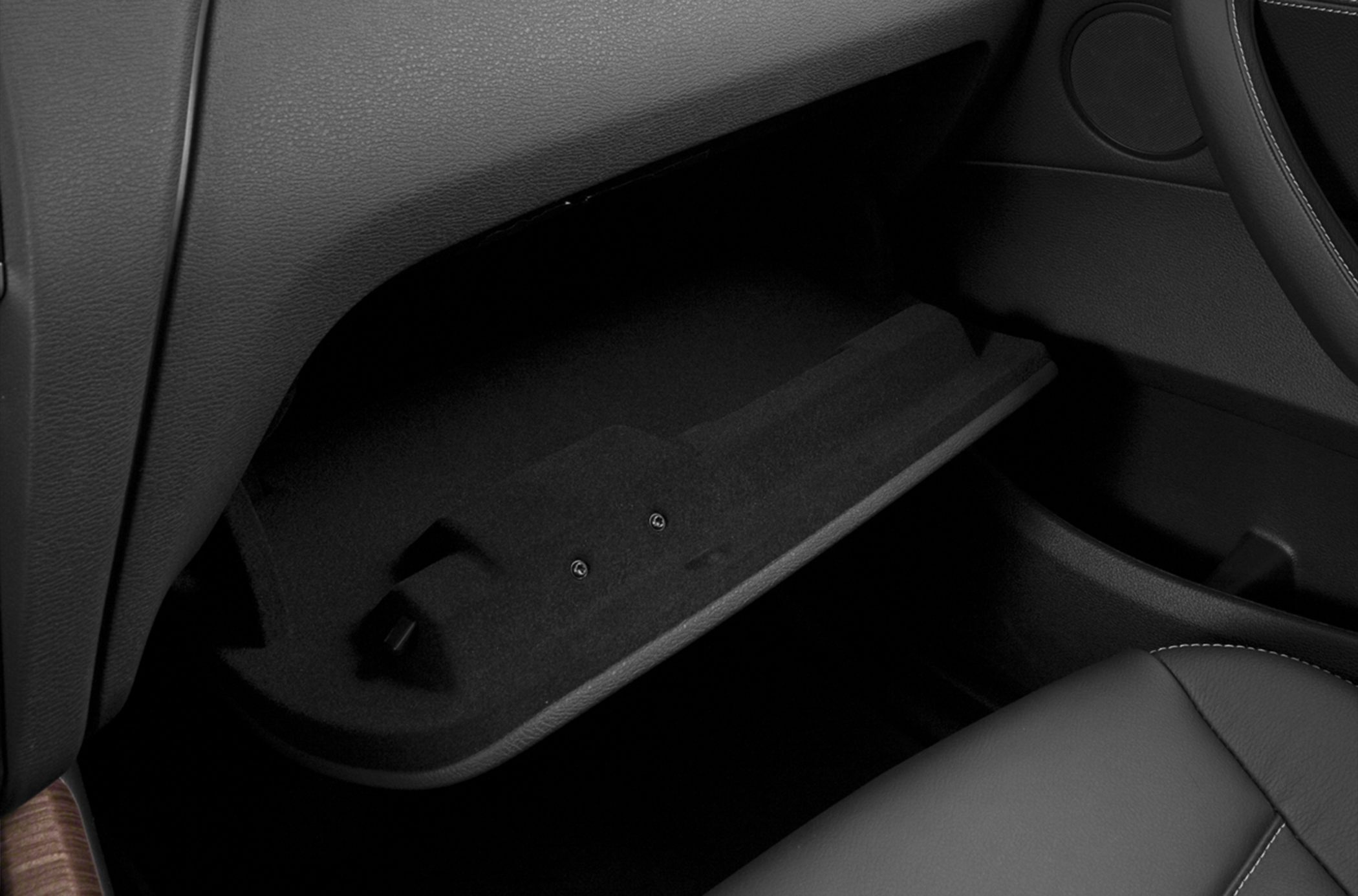 Open glove compartment with textured lining and visible leather seat stitching