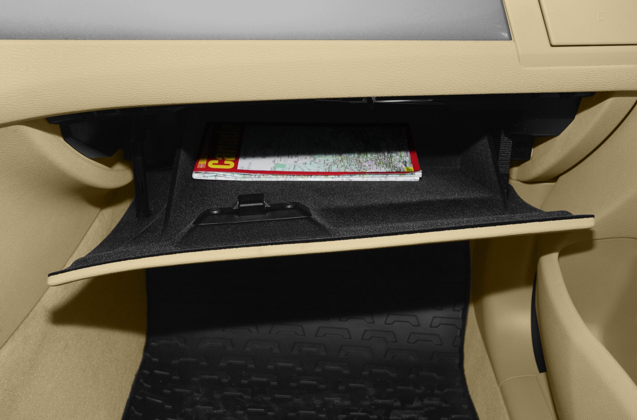 Open glove box with map on beige interior dashboard and floor mat
