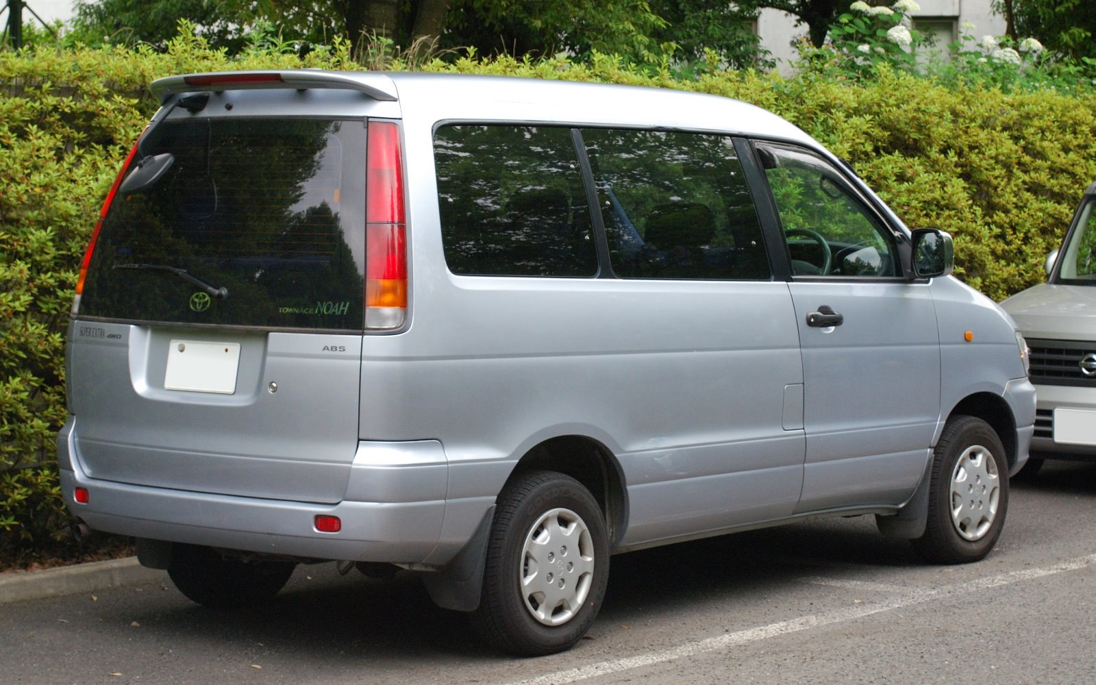 Silver minivan rear-side with dark tinted windows and vertical taillights