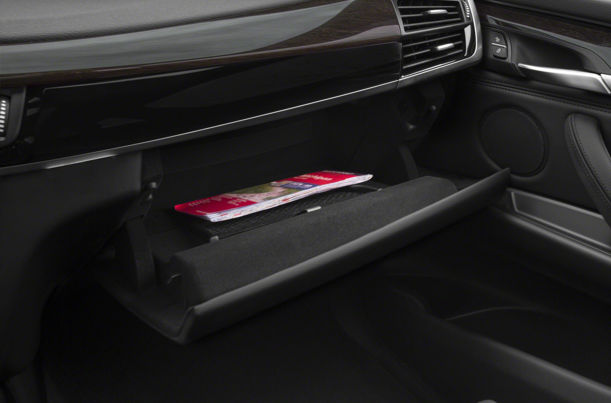 Open glove compartment with a magazine inside, part of a luxury SUV interior