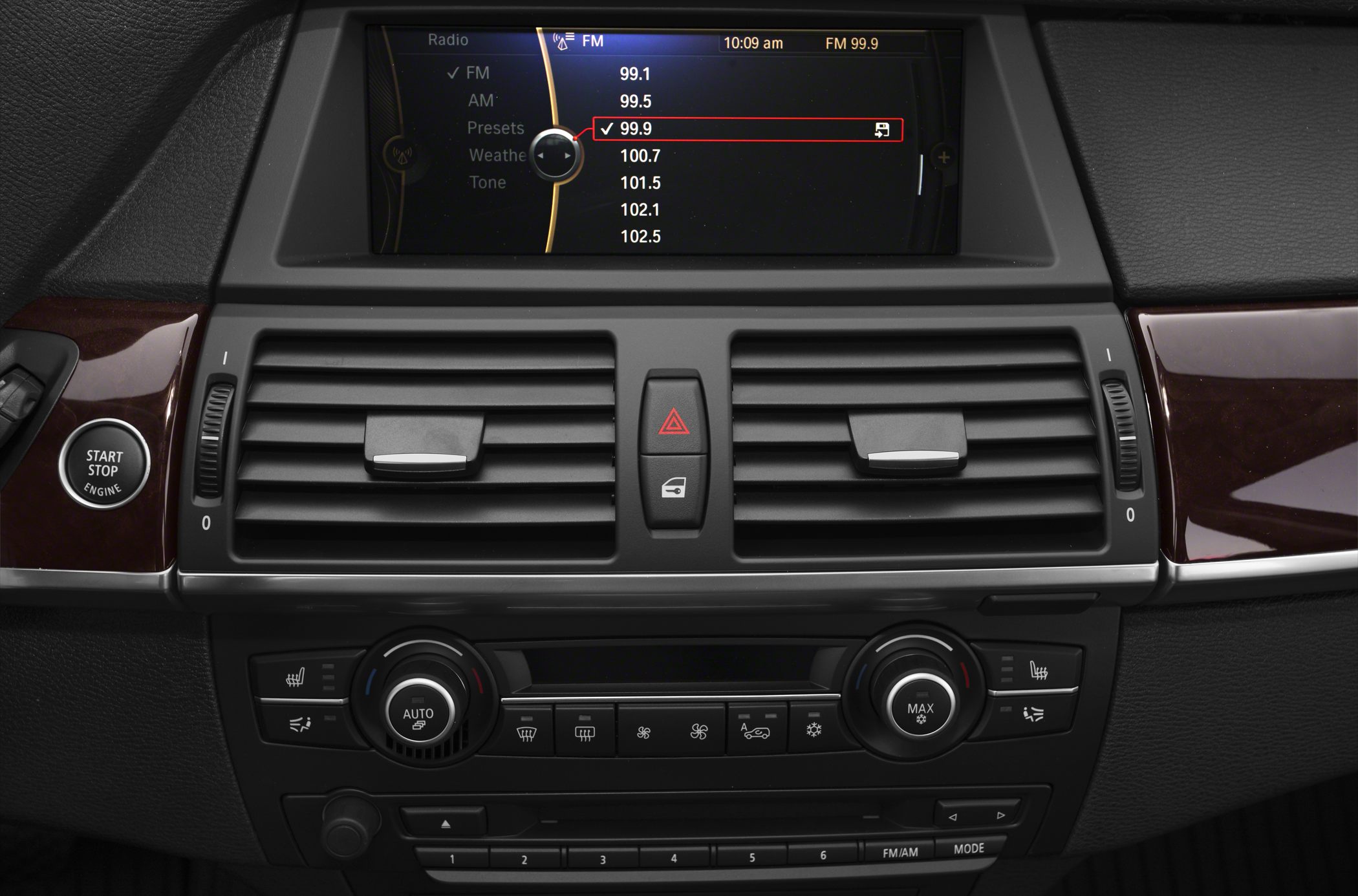 Infotainment screen, climate controls, and start/stop button on car dashboard