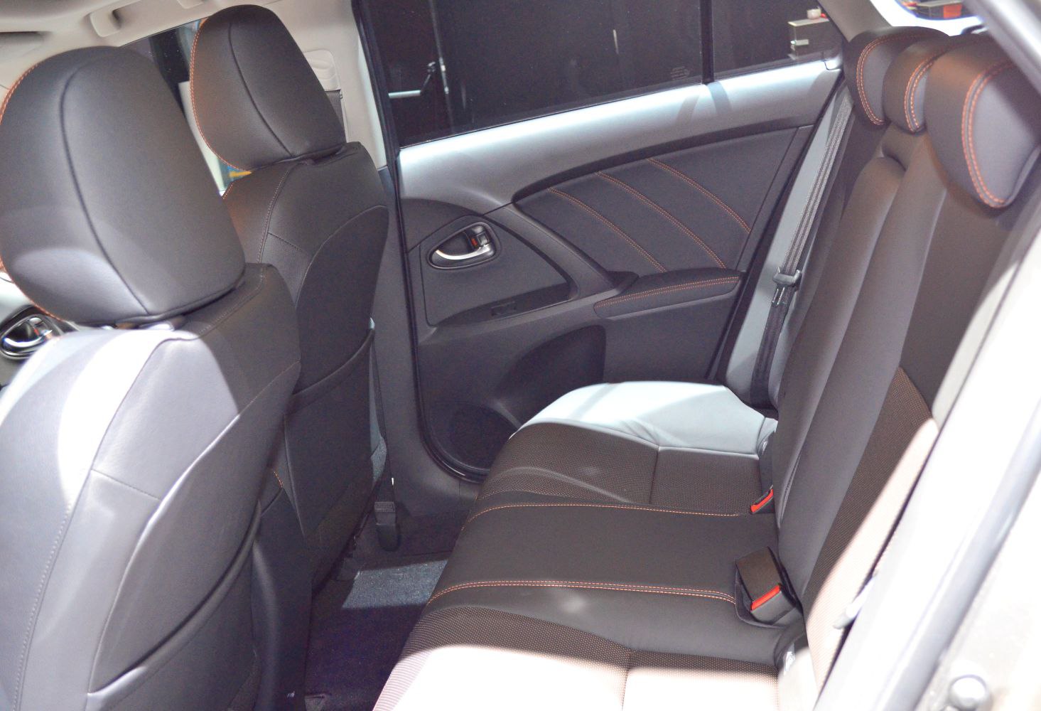 Rear seat interior with black leather upholstery and orange contrast stitching
