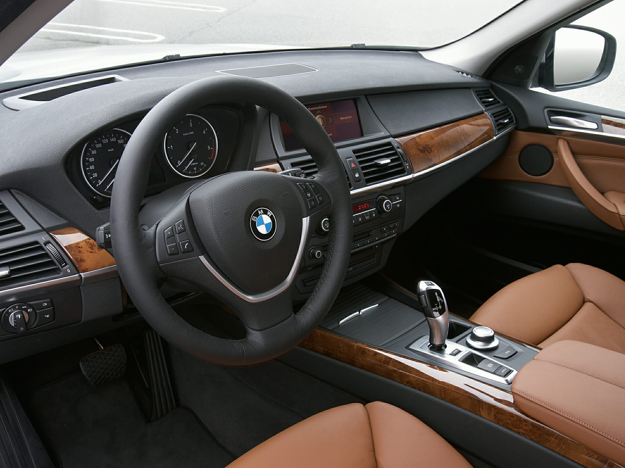 Luxury interior with steering wheel, dashboard, wood trim, and gear shifter