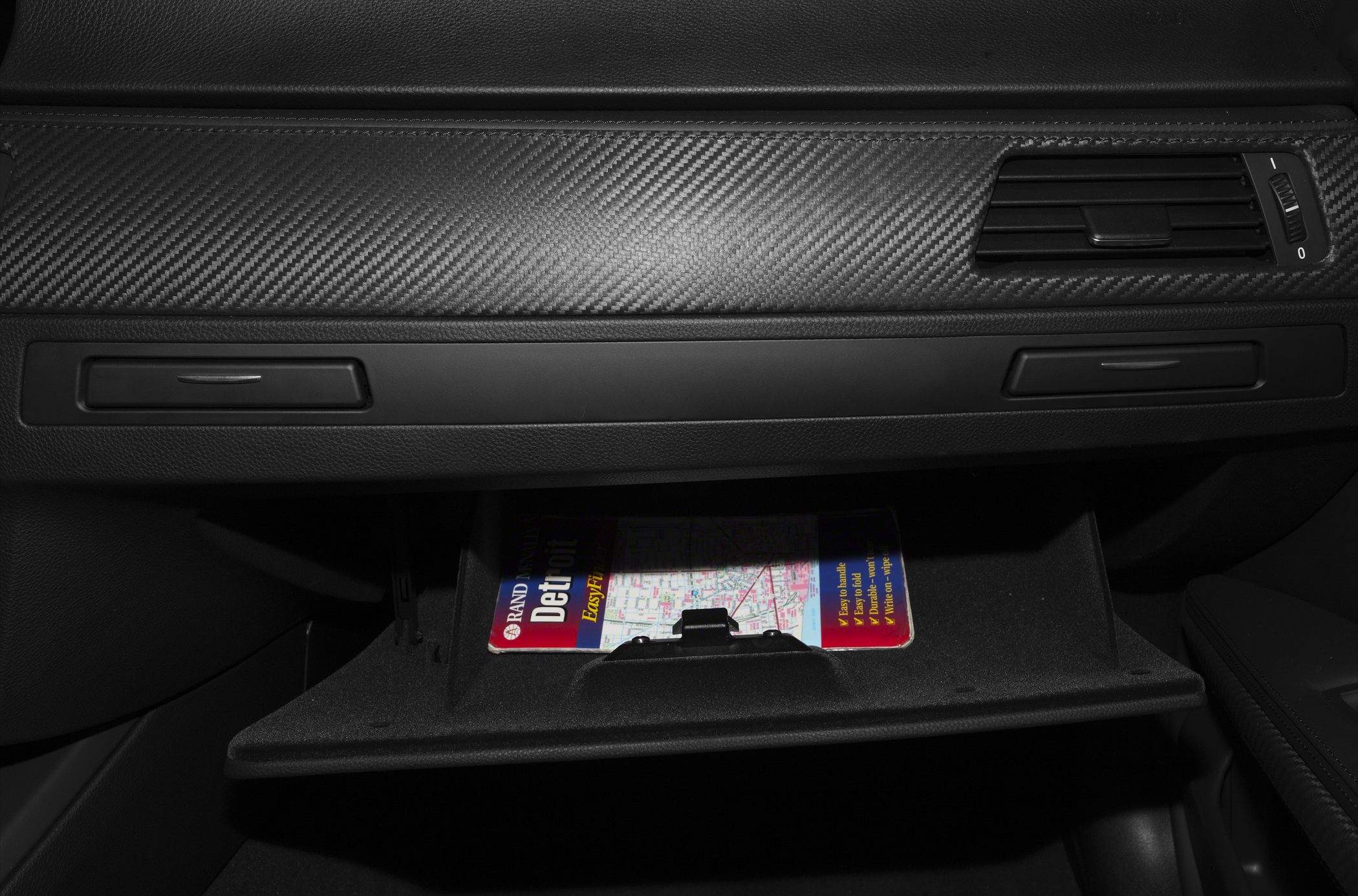 Carbon fiber dashboard trim and open glovebox with map inside