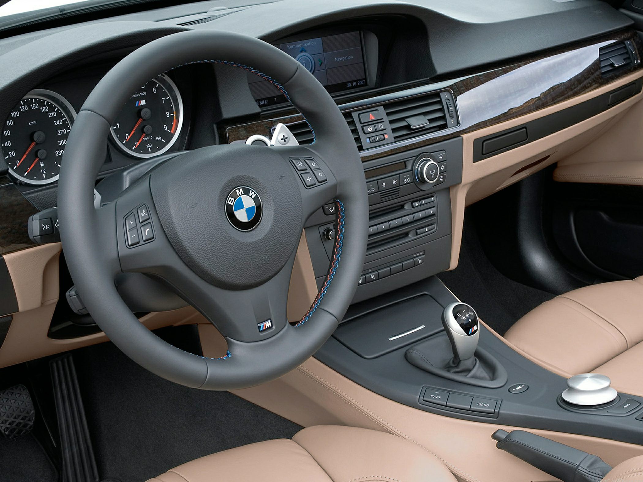 Manual gear shift and steering wheel with M badge in a luxury tan leather interior