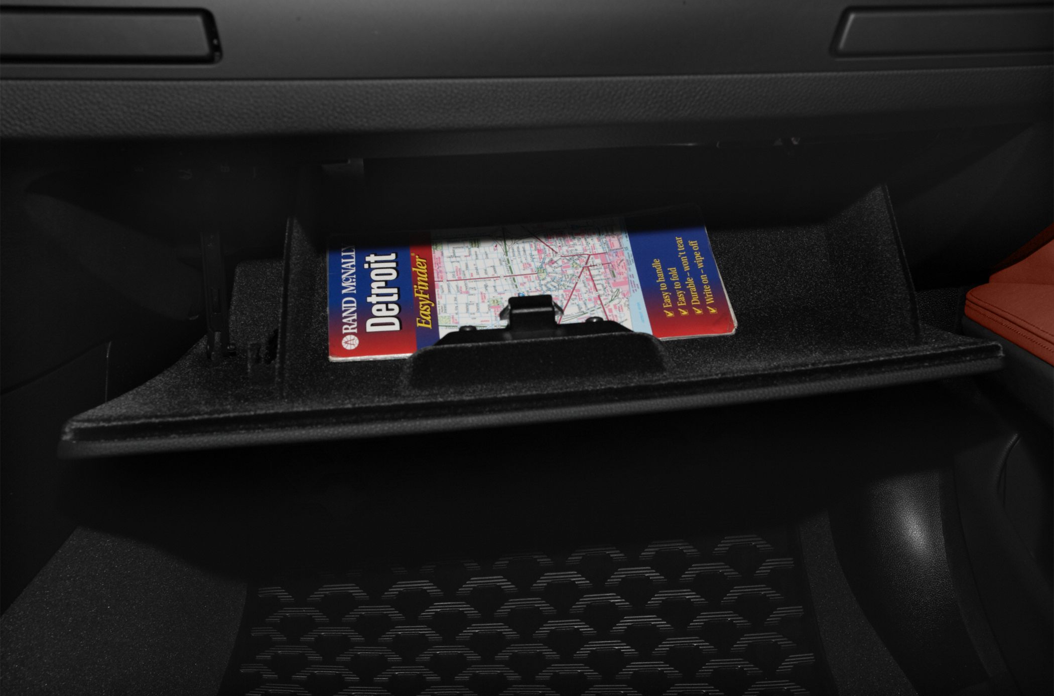 Close-up of glove box storage with a folded map inside