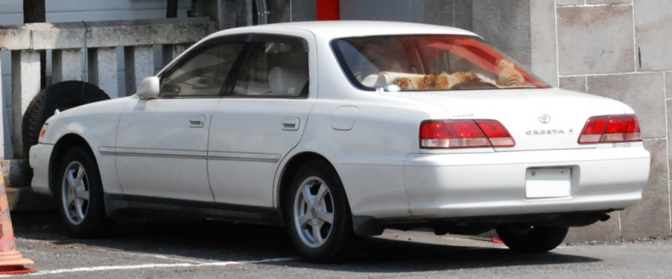 Rear side view of white four-door sedan with alloy wheels and classic taillights