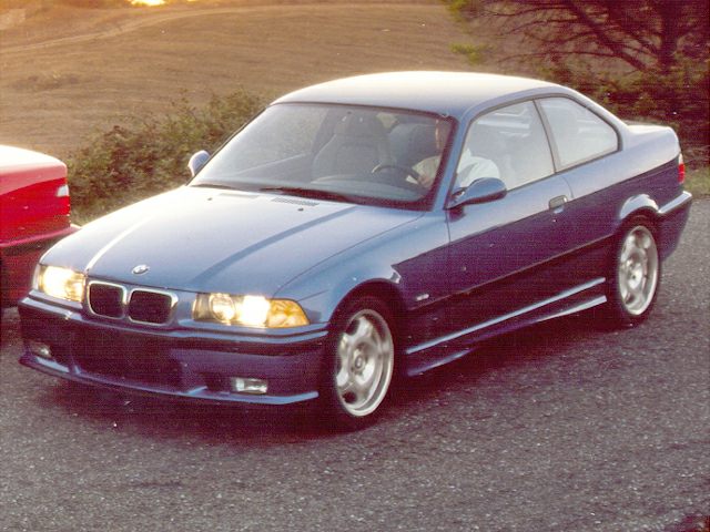Blue sporty coupe with illuminated headlights and distinctive front grille