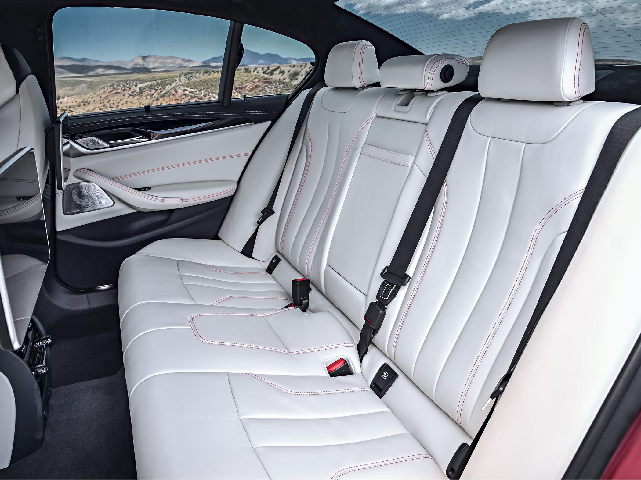 White leather rear seats with red stitching and modern door panel