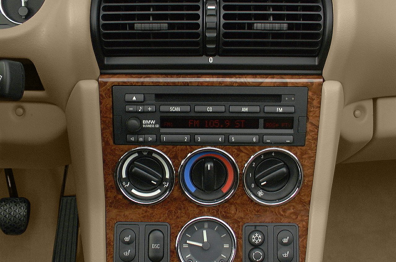 Analog clock, climate dials, vintage radio on wood trim dashboard