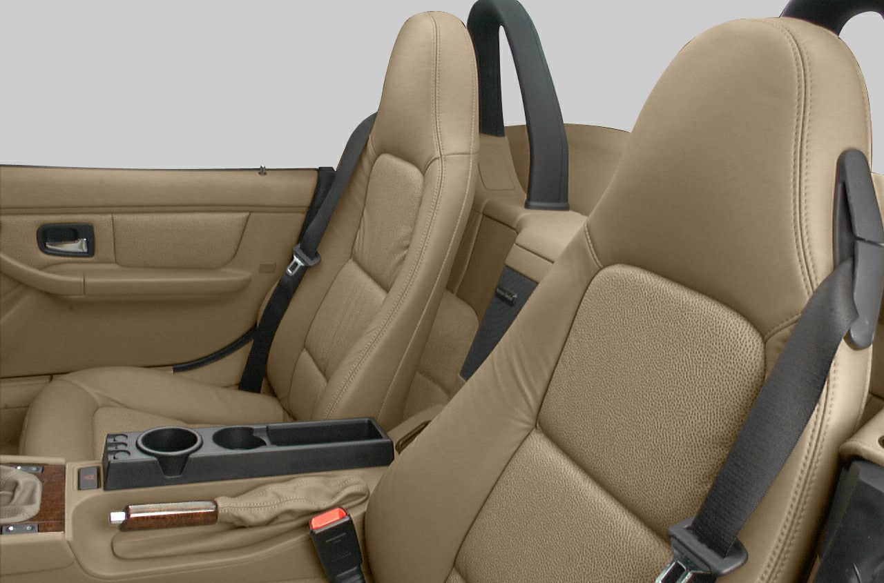 Close-up of beige leather seats and center console with seat belts