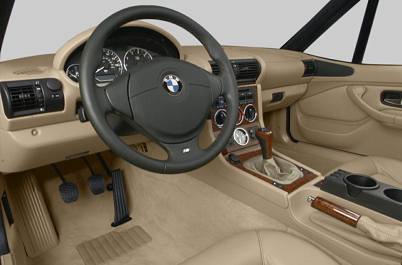 Beige interior dashboard and steering wheel with manual gearshift and wood trim