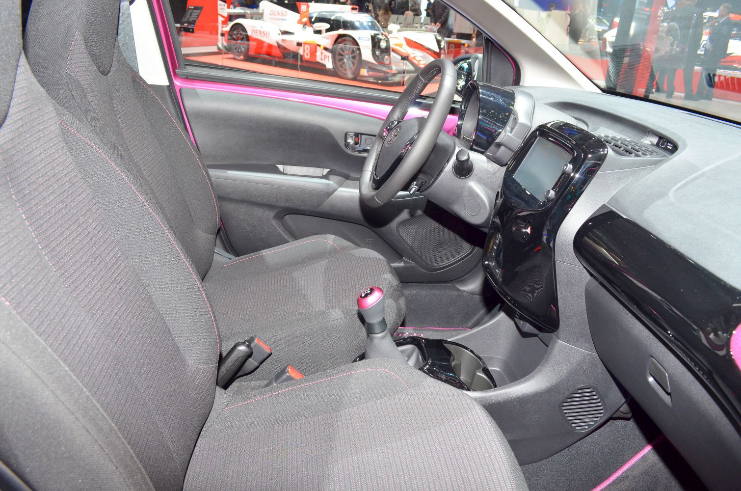 Compact car interior with dashboard, seating, and manual gear shift
