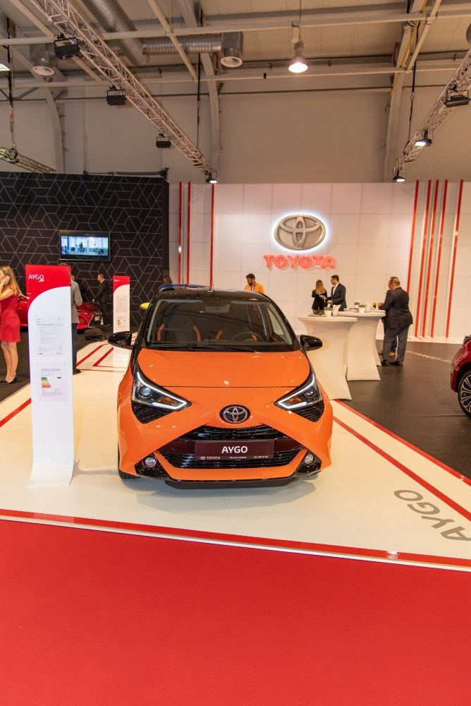 Orange compact hatchback with distinctive 'X' front design and LED headlights