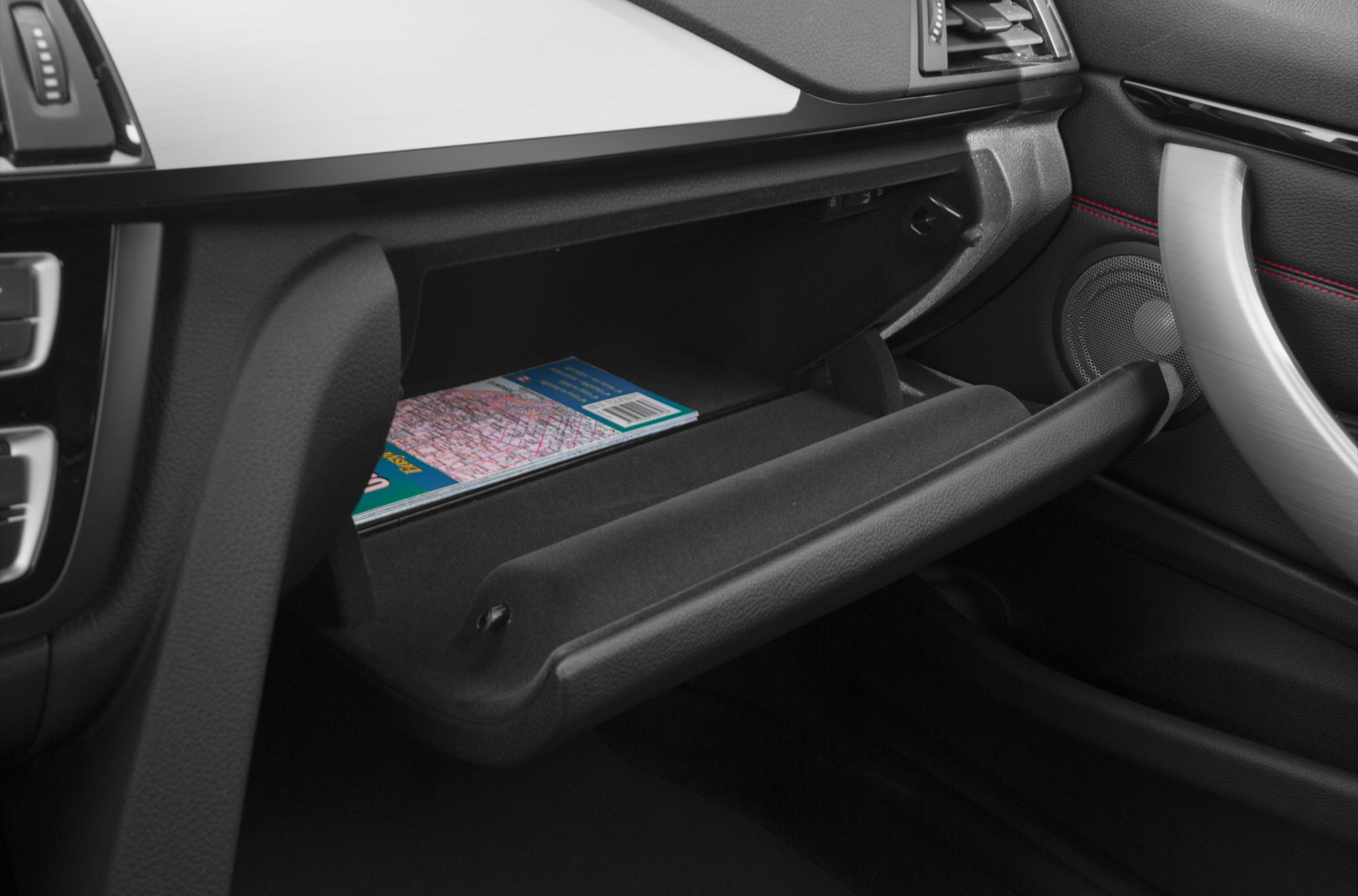 Opened glove box inside car interior with visible map