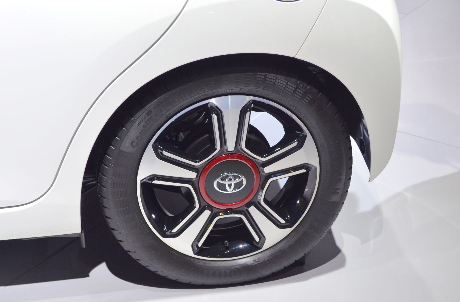 Close-up of a black and chrome alloy wheel with red trim on a white car.