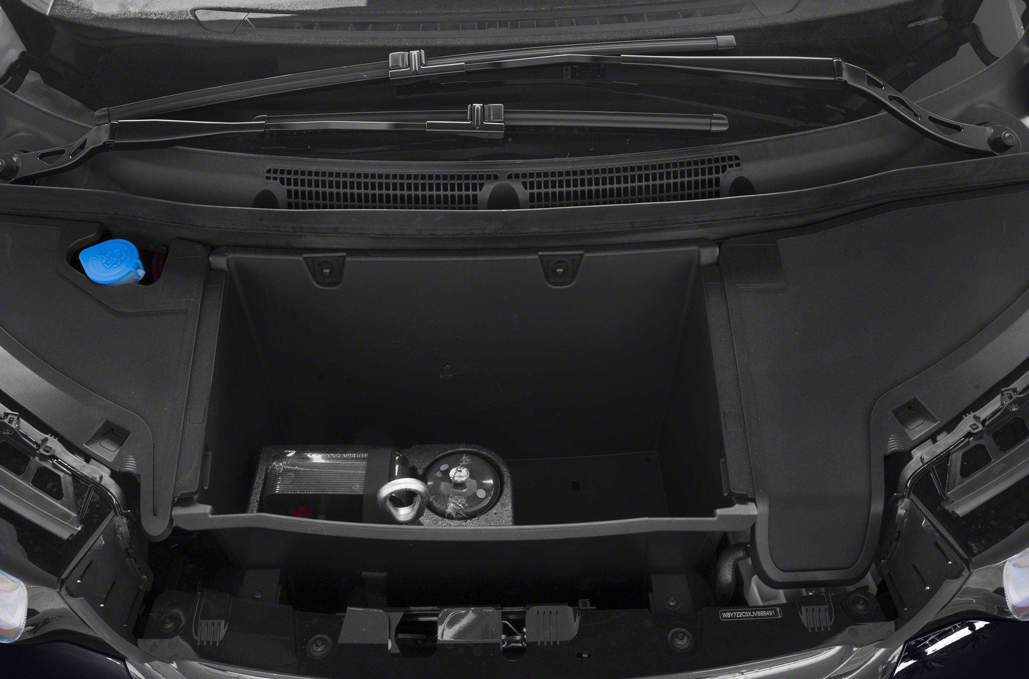 Interior view of front trunk storage compartment with components and windshield wipers