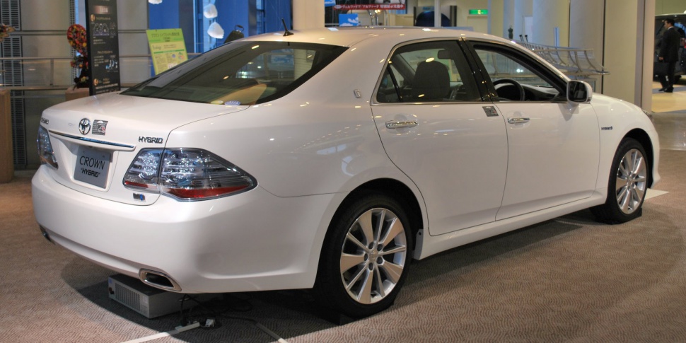 Hybrid sedan rear-side view with alloy wheels and hybrid badge.