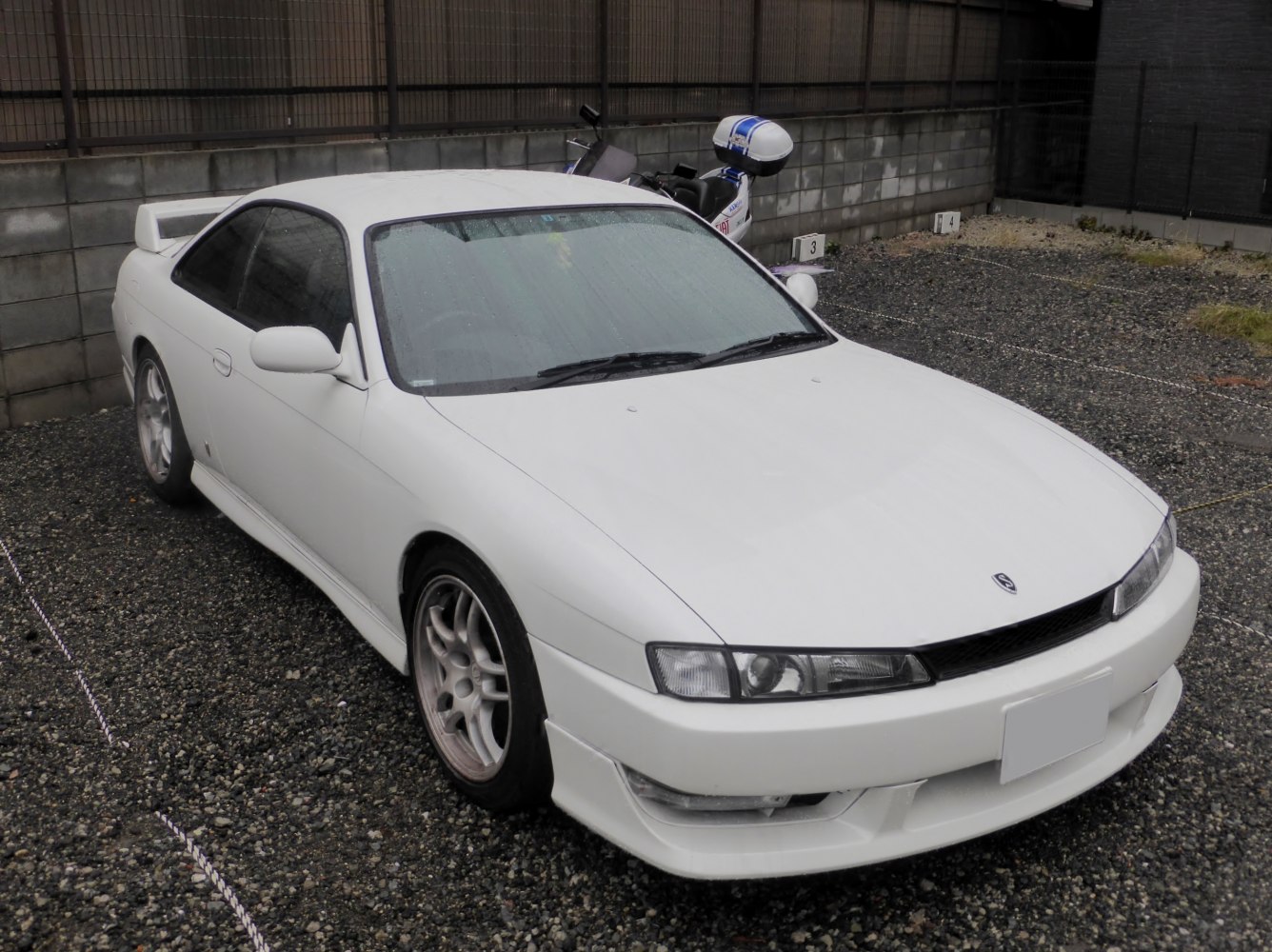 White sports coupe with rear spoiler and alloy wheels
