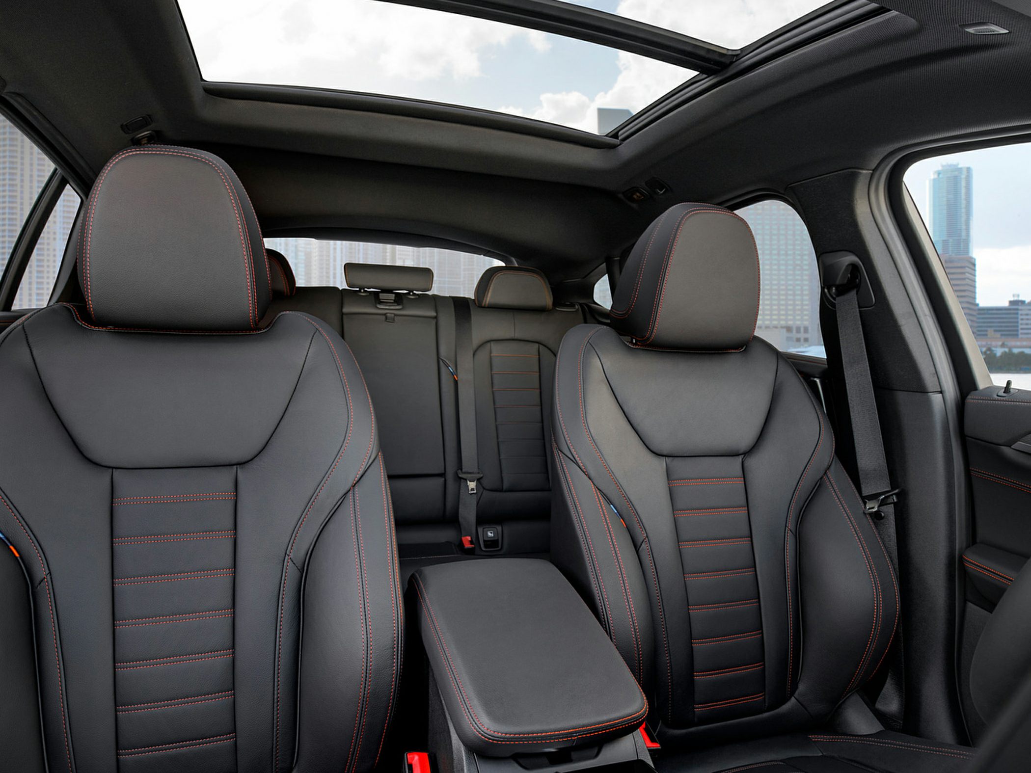 Black leather car seats with red stitching and panoramic sunroof