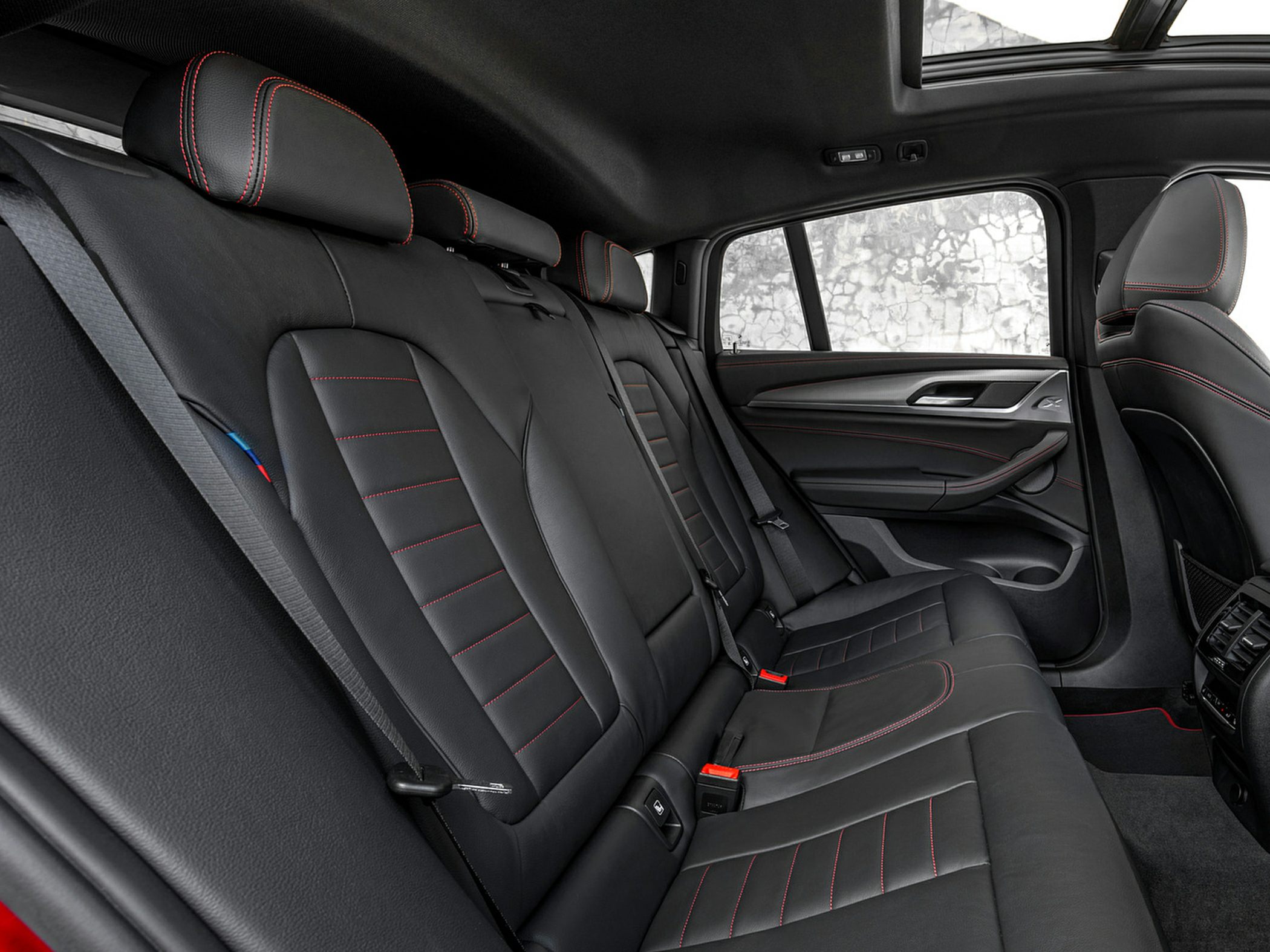 Black leather rear seats with red stitching and spacious design including a sunroof.