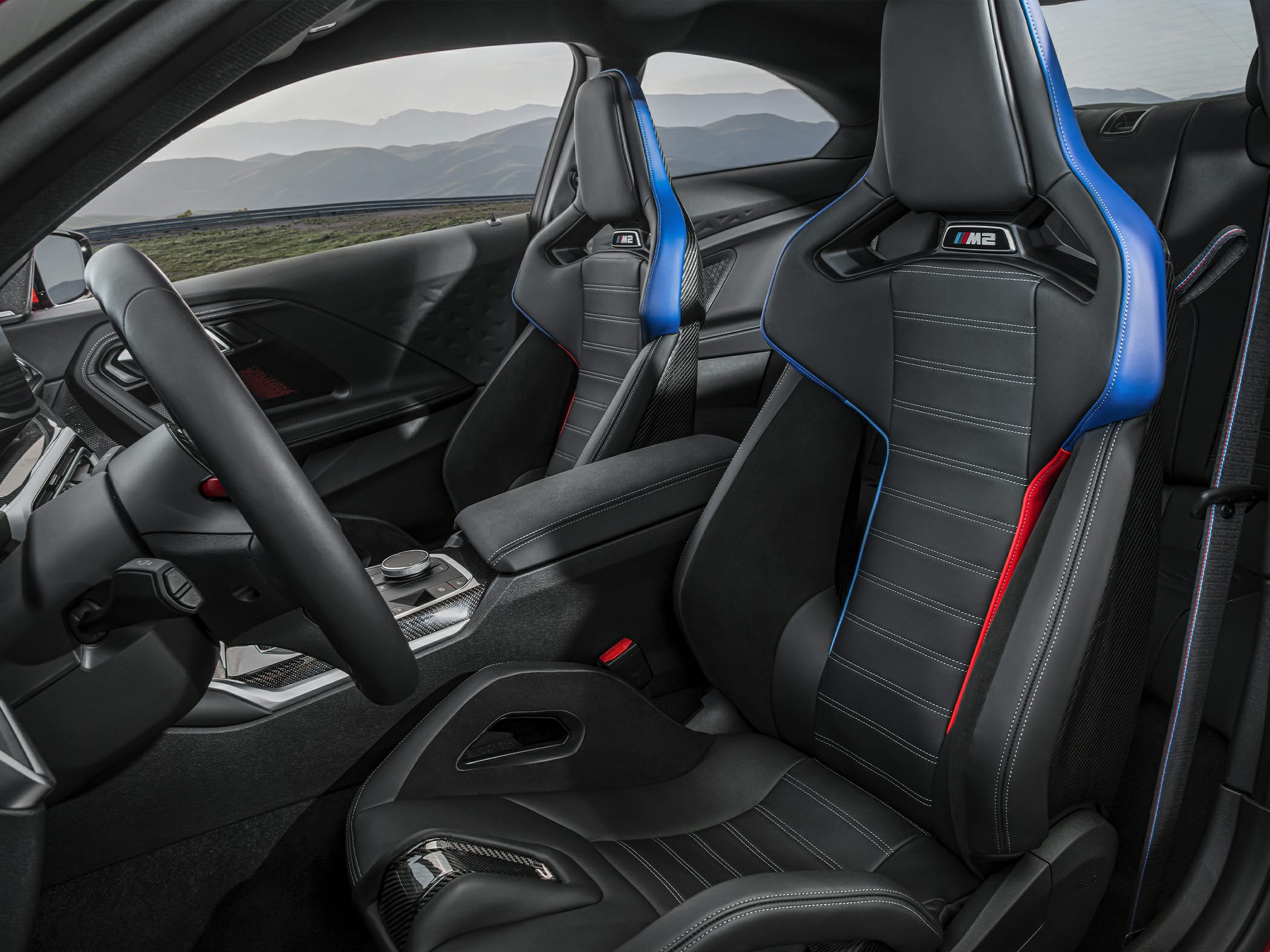 Sporty racing seats with M2 logo and carbon fiber elements inside a modern cockpit