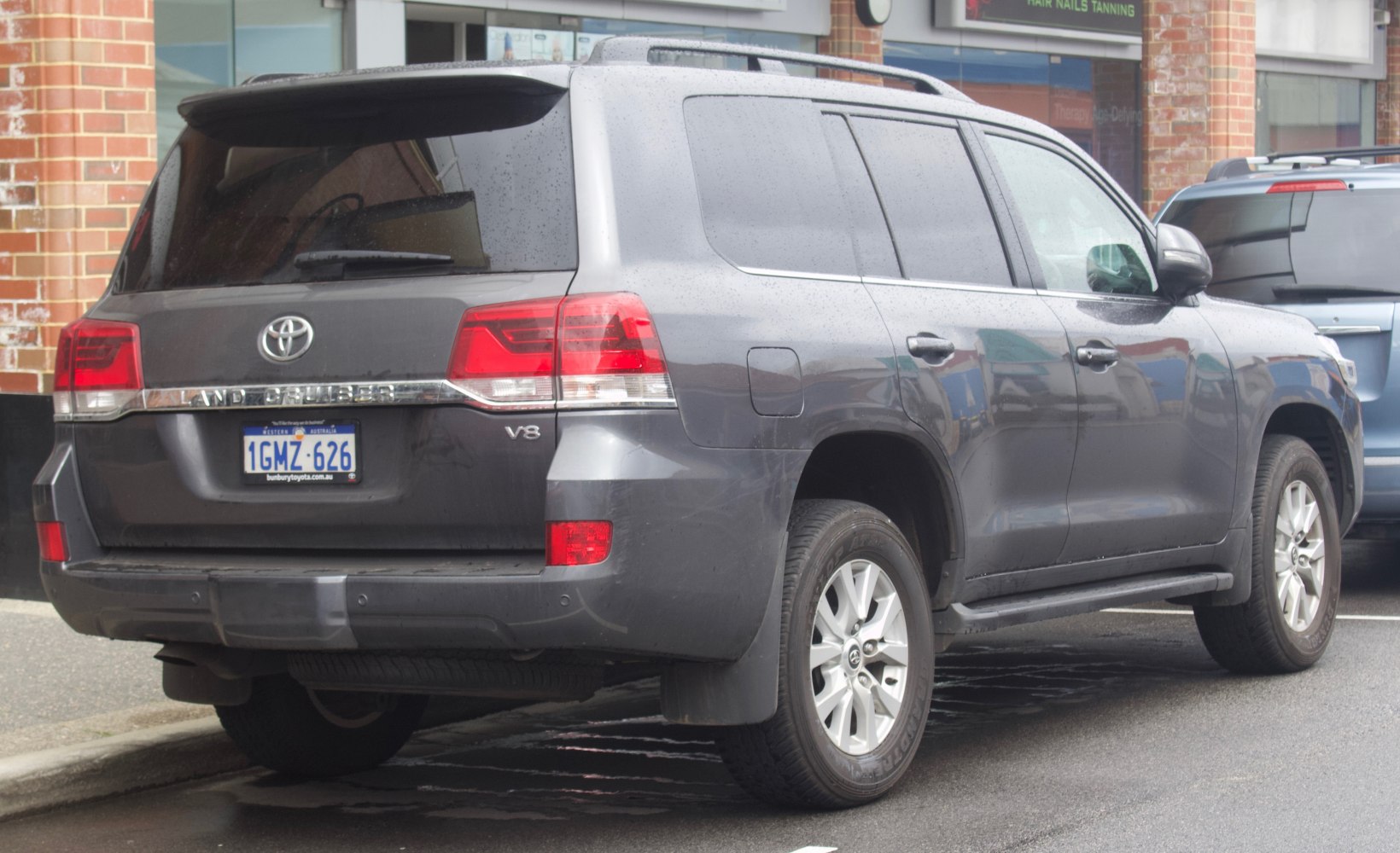 Rear side view of a dark gray SUV with V8 badge